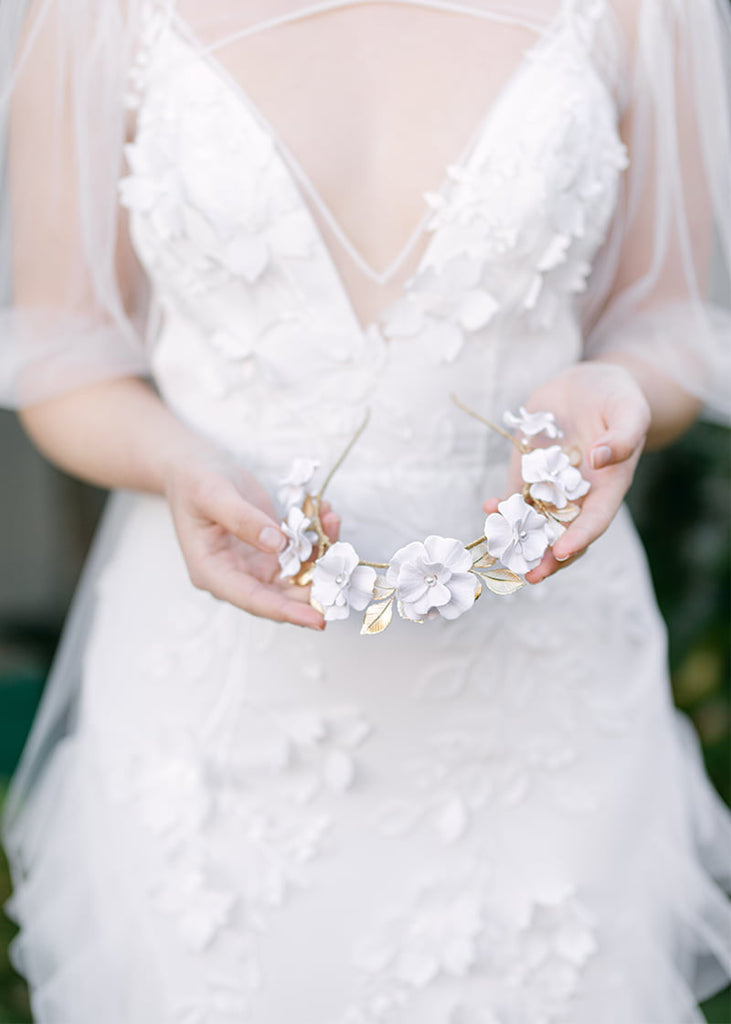 Handmade flowers of different sizes in a row with leaves backing the flowers.