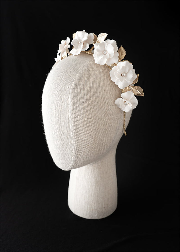 Seven handmade flowers on a thin headband in a tiara with metal leaves.