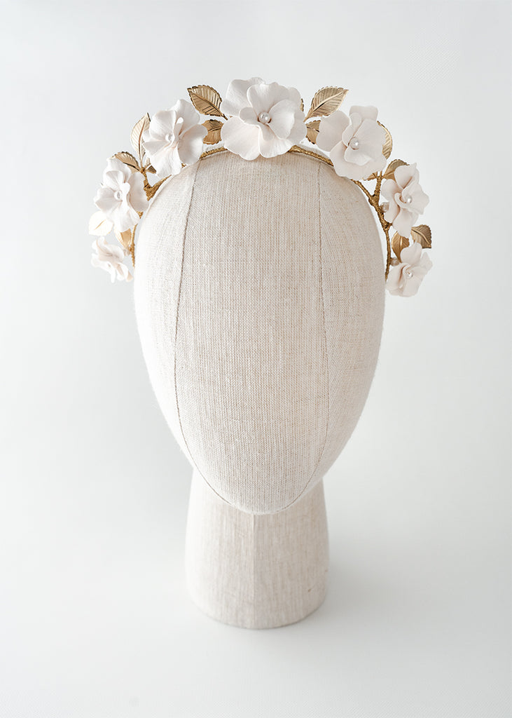 Headpiece with seven flowers in a row with pearls in the middle and leaves.