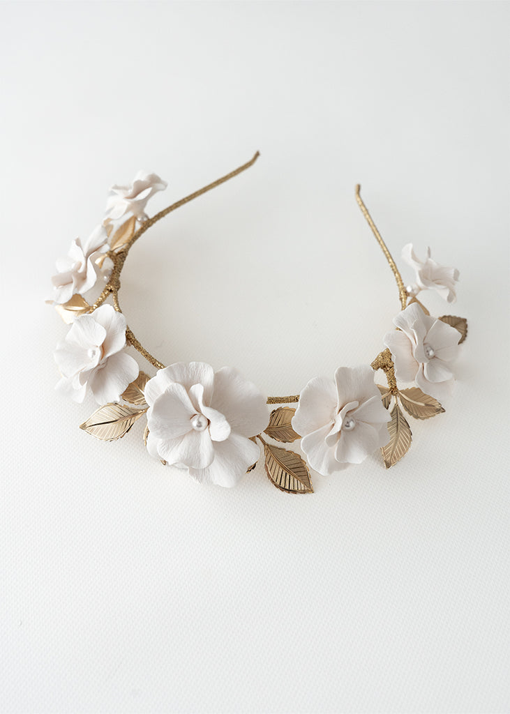 Tiara with handmade flowers in a row with gold leaves behind.