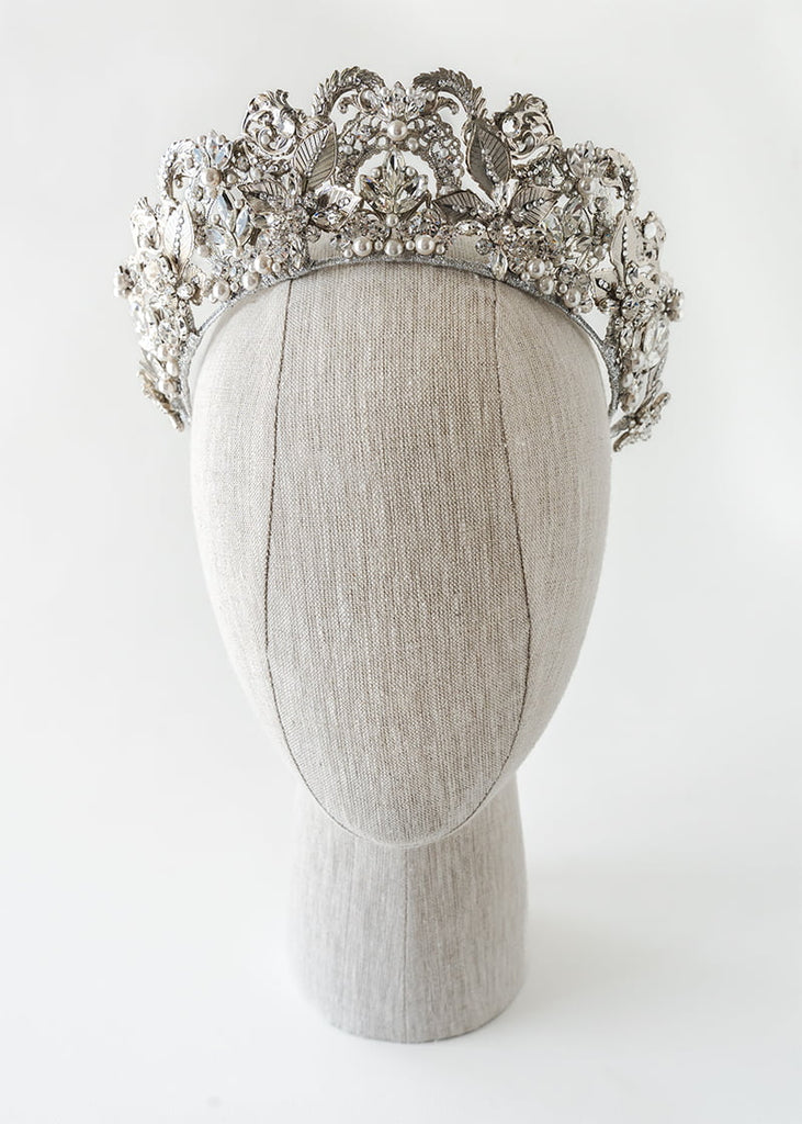 Olympia statement tiara is 6 cm tall with an abundance of hand beading of rhinestone and pearls. It has metal filigrees and leaves for the base of the design.