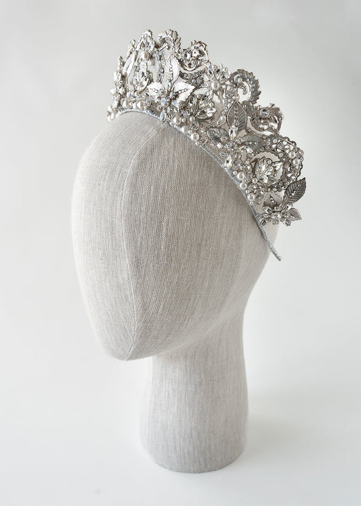 Olympia statement tiara is 6 cm tall with an abundance of hand beading of rhinestone and pearls. It has metal filigrees and leaves for the base of the design.