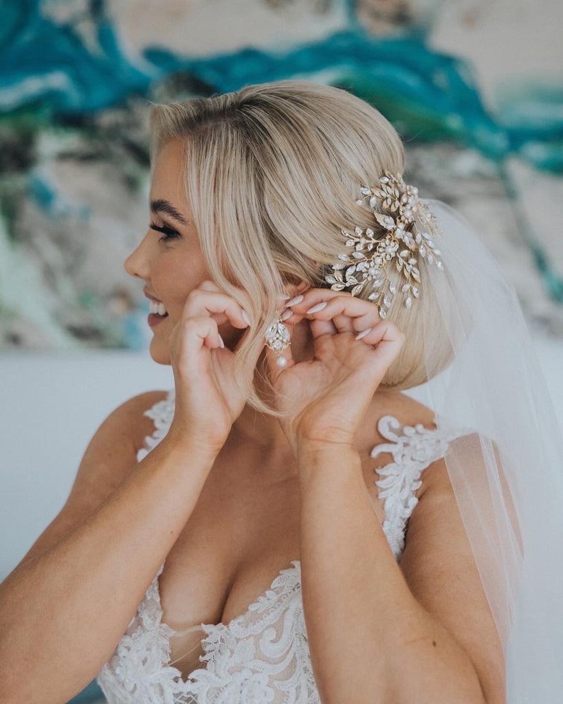 Photo of real Bride Sarah on her wedding day putting on her earrings.